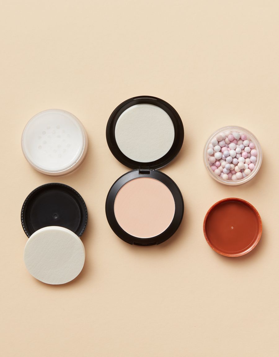 Flat lay of powder compacts on a beige surface