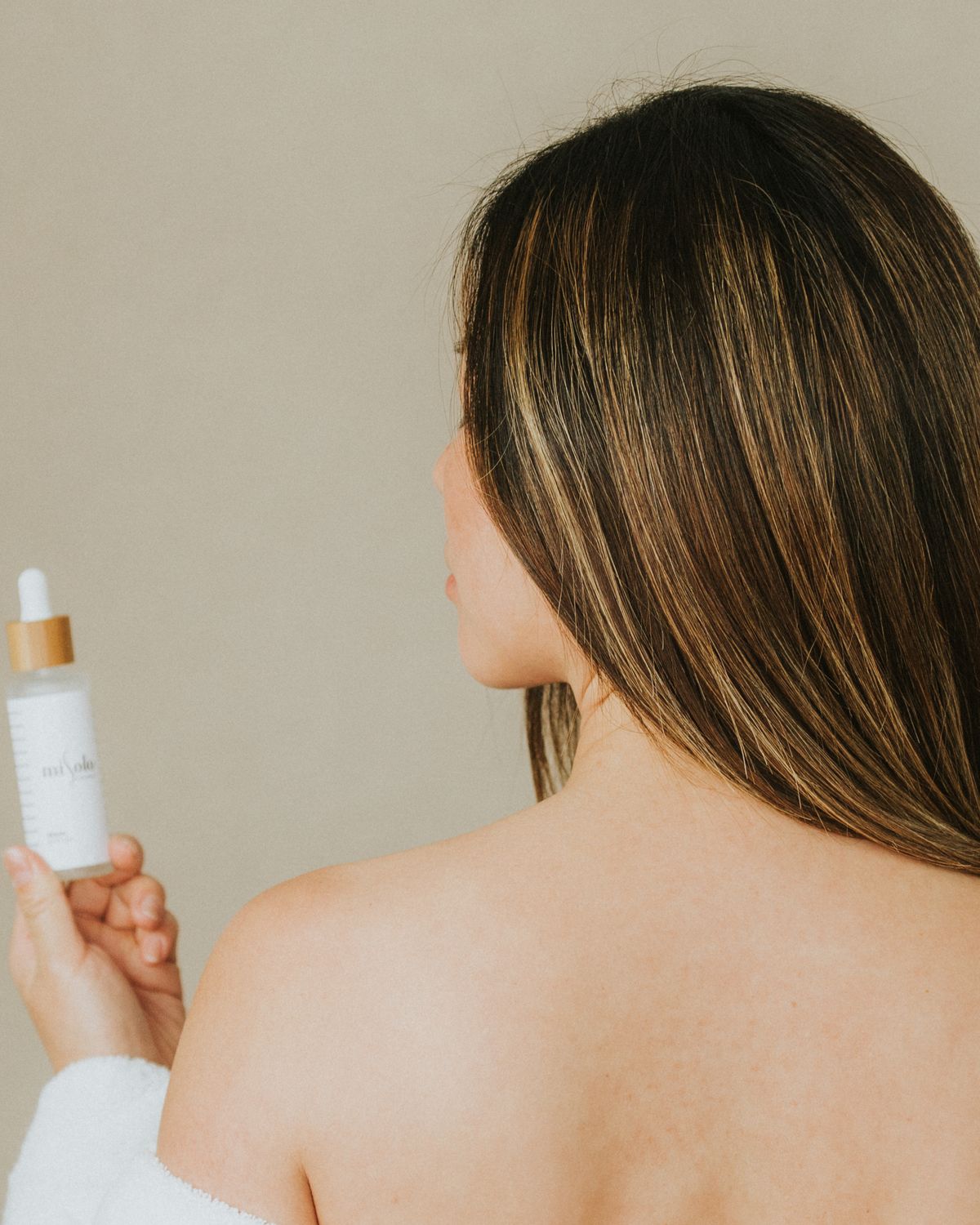 Model holding a minimalist skincare bottle